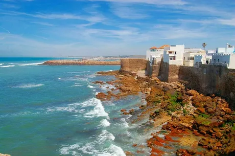 9 Days Morocco Tour From Casablanca/Hassan II Mosque in Casablanca during sunset – start of 9 days Morocco tour/Historic Oudayas Kasbah in Rabat, one of Morocco’s imperial cities/View of the ancient medina in Fes, Morocco – a highlight of imperial city tour/Archaeological ruins of Volubilis near Meknes, included in Morocco itinerary/Tourists on a camel trek in the Sahara Desert dunes of Merzouga at sunset/Luxury desert camp in Merzouga with Berber tents and lanterns under the stars