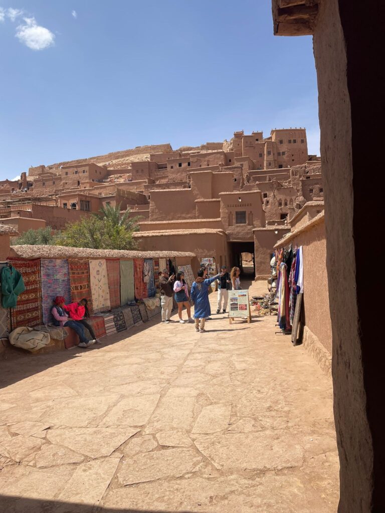 4 Day Marrakech to Fes,,Camel caravan crossing the golden Erg Chebbi dunes at sunset in Merzouga, Morocco Traditional Berber desert camp under starry skies in the Sahara Desert Scenic view of the High Atlas Mountains on the road from Marrakech to Merzouga UNESCO World Heritage Ait Benhaddou Kasbah near Ouarzazate, Morocco Tourists exploring Todra Gorge with towering cliffs in Morocco Lush Ziz Valley and palm groves on the way from Merzouga to Fes Tourists enjoying a 4-day Marrakech to Fes desert tour by jeep and camel