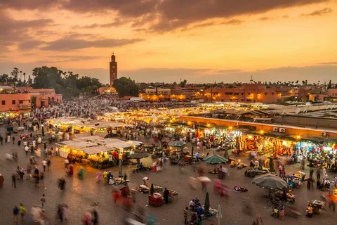 A vibrant, sun-drenched shot of a Jemaa el-Fnaa square in Marrakech at dusk