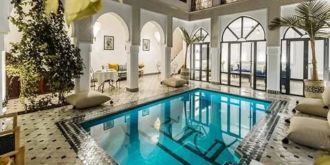 A tranquil, elegant shot of a private riad courtyard with a plunge pool and orange trees)
